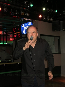 Paul the Rock God performing energetic vocals live on stage at a karaoke event
